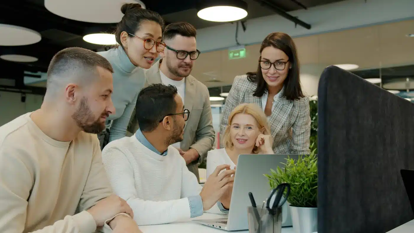 Diverse business team collaborating around a laptop in a modern office