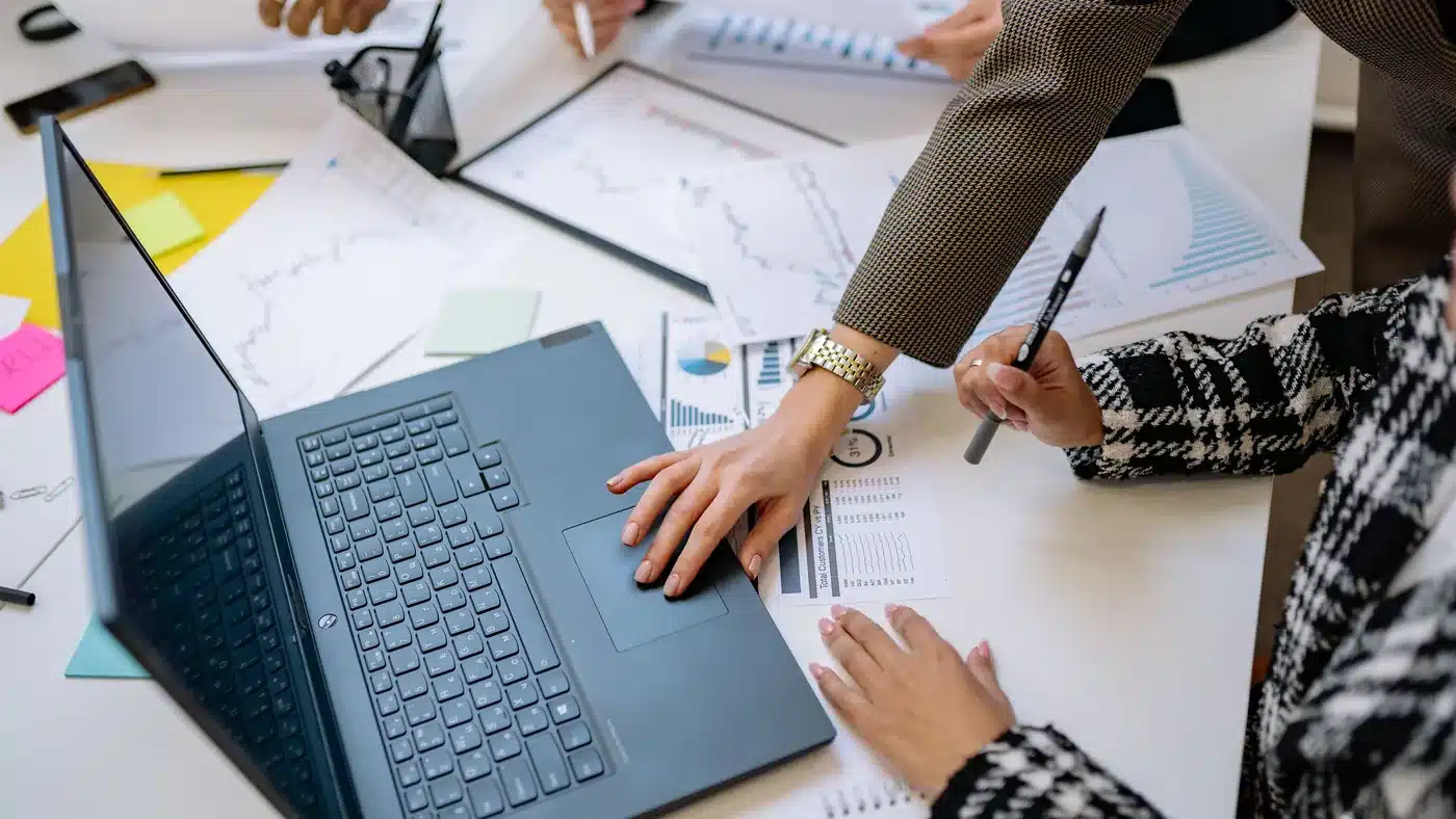 Business team reviewing reports and a laptop during a supplier comparison meeting