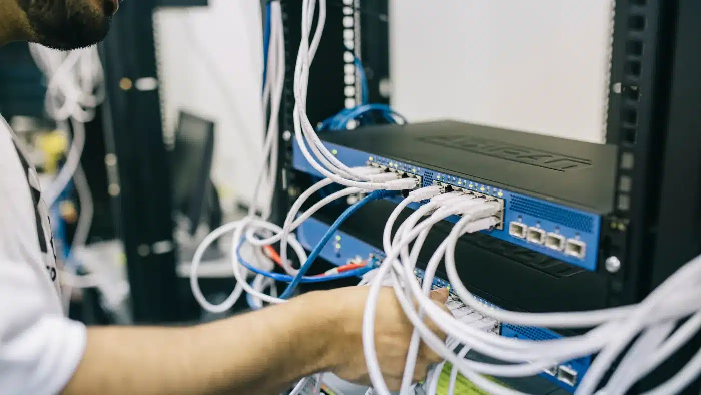Network technician configuring Ethernet cables in a business server rack