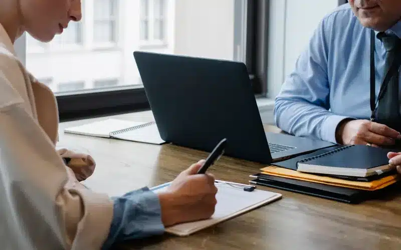 Business advisers agreeing a staged delivery plan using documents and a laptop