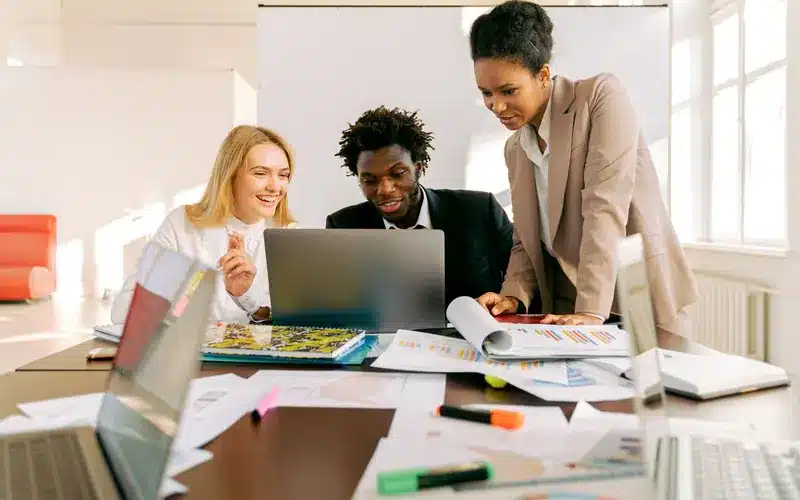 Business team collaborating around a laptop and shared documents