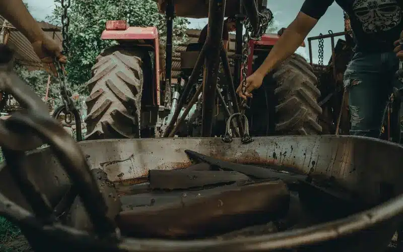 Agricultural specialists repairing machinery beside a tractor