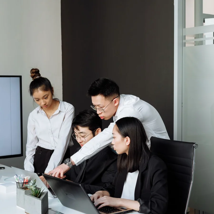 Business colleagues discussing work around a laptop in a modern office