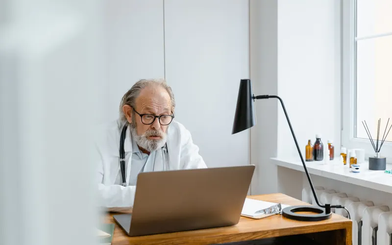 Senior doctor using a laptop in a professional medical office