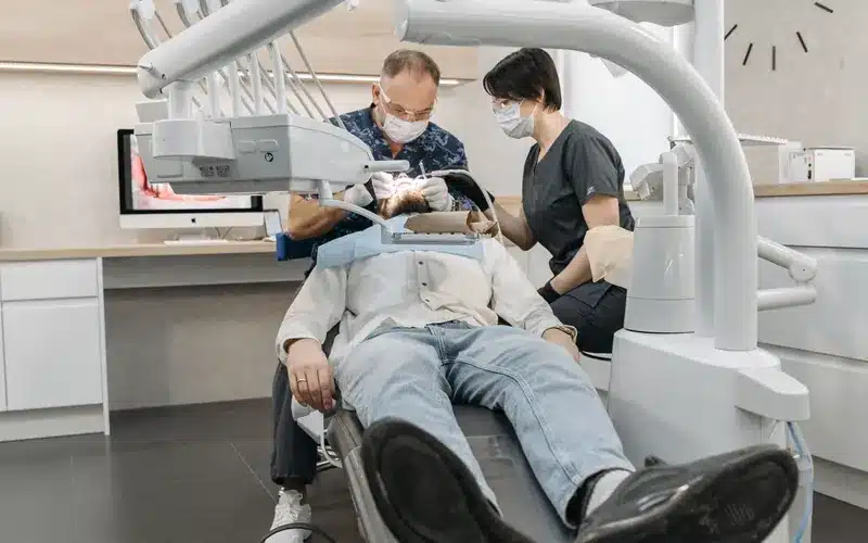 Dentist and assistant working with clinical equipment in a dental practice