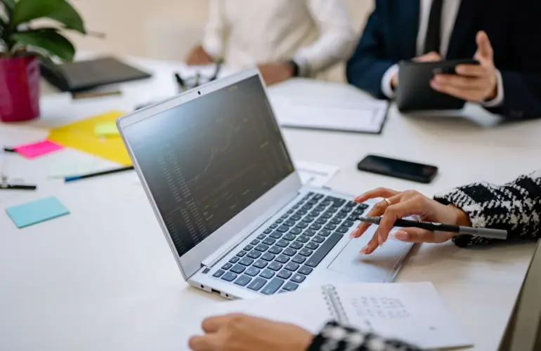 Business colleagues review financial information on a laptop during a meeting